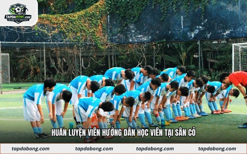 Huấn luyện viên hướng dẫn học viên tại sân cỏ